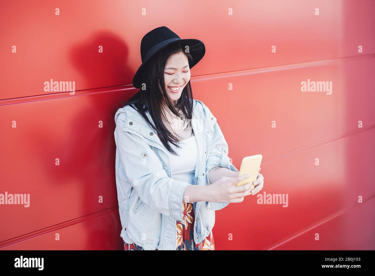 Asiatisches Mädchen mit Handy im Freien - Glückliche tausendjährige Chinesin hat Spaß mit neuen Trends Smartphone-Apps Stockfoto