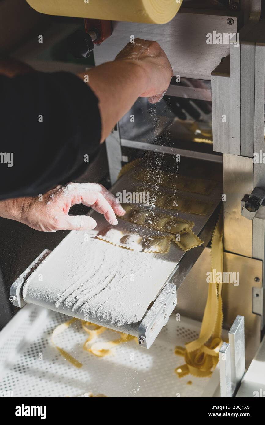 Herstellung von Ravioli, Tortellini und Cappelletti, typisch italienische Pasta - die Hände des Küchenmehls, den Ravioli gerade von der produziert hat Stockfoto