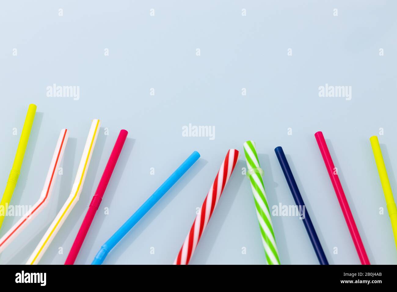 Bunte Trinkhalme aus Kunststoff auf blauem Glas. Das Konzept der Plastischen Überschwemmung der Welt, Raum für Text Stockfoto