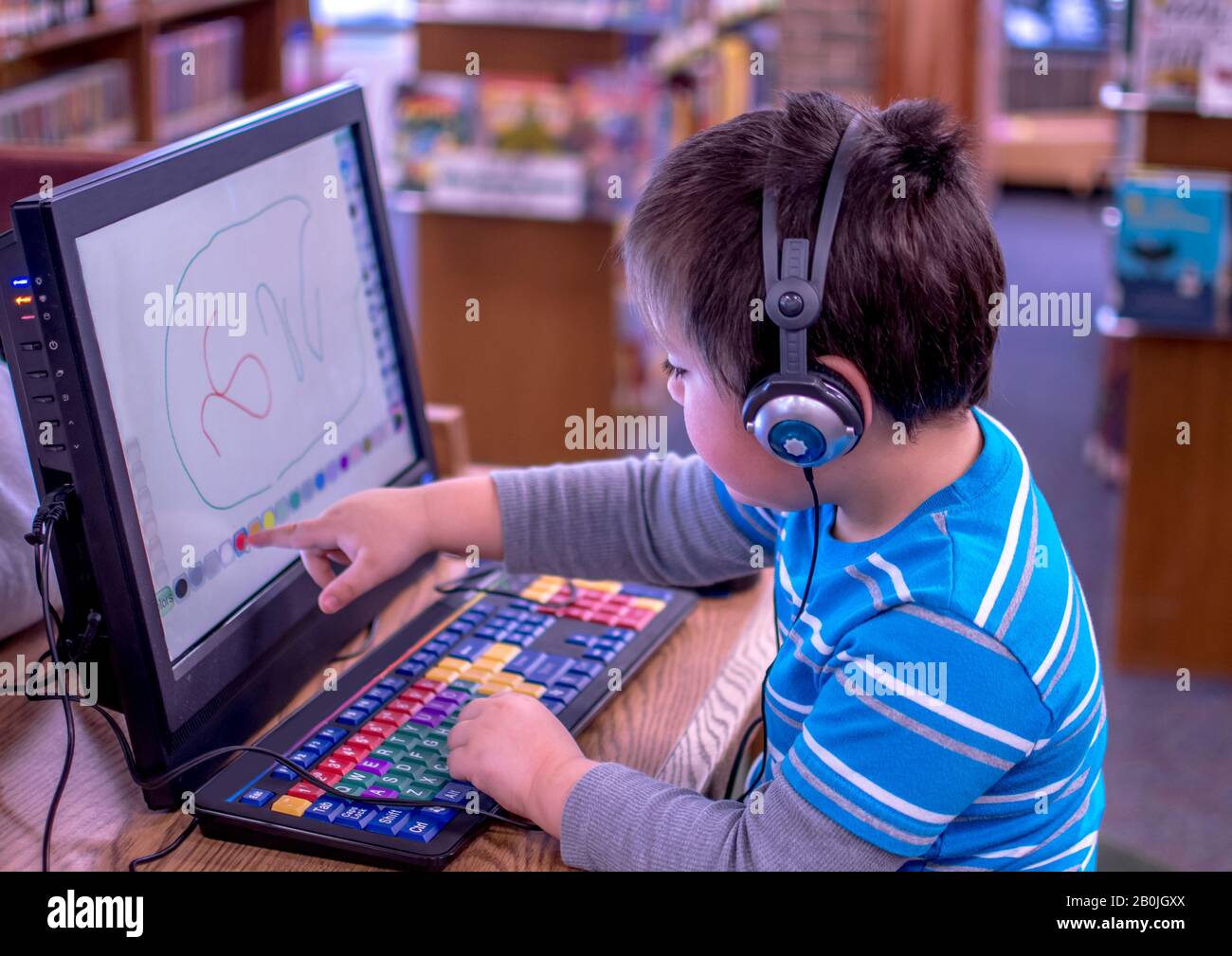 Ein kleiner Junge spielt auf einem Touchscreen-Computer in der örtlichen Bibliothek Stockfoto