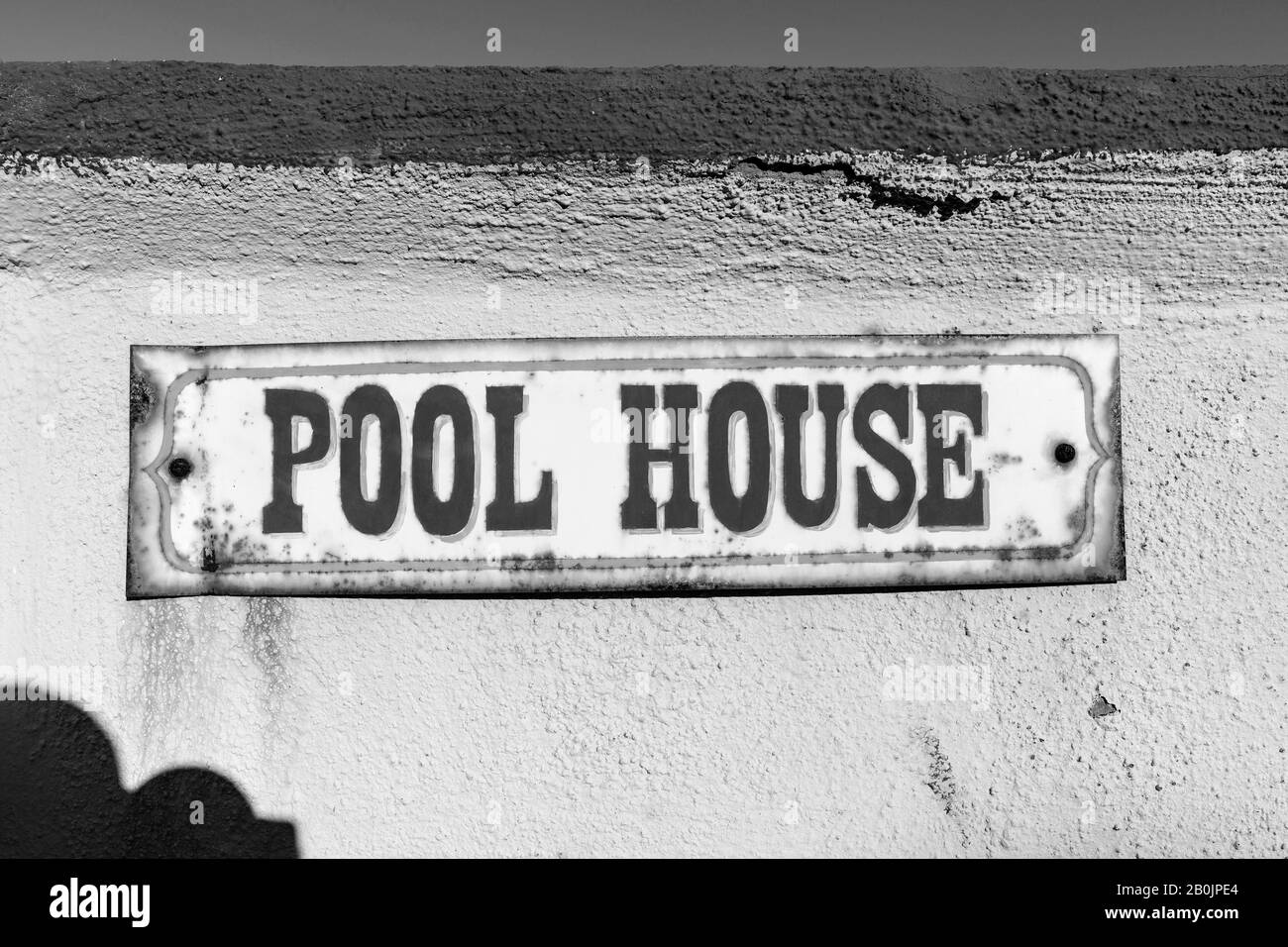 Schwarz-Weiß-Foto von altem rostigen Poolhausschild an der stuckierten Wand. Stockfoto