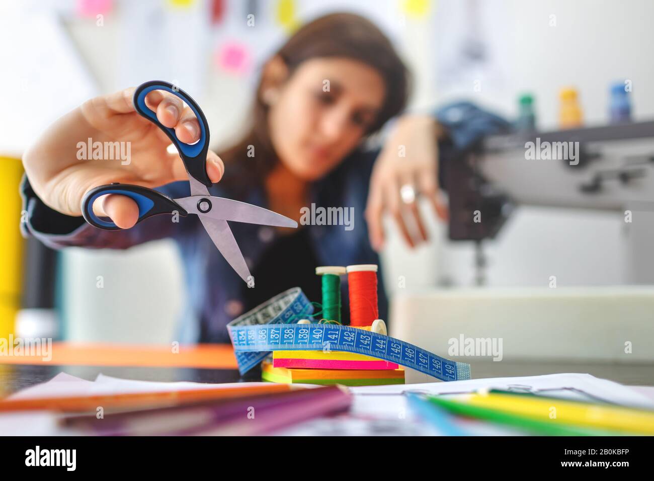 Schneidegeräte messen Band, Schere und Gewinde und Nadel in der Werkstatt. Geringe Schärfentiefe auf dem Modedesigner-Symbol. Modekonzept. Stockfoto