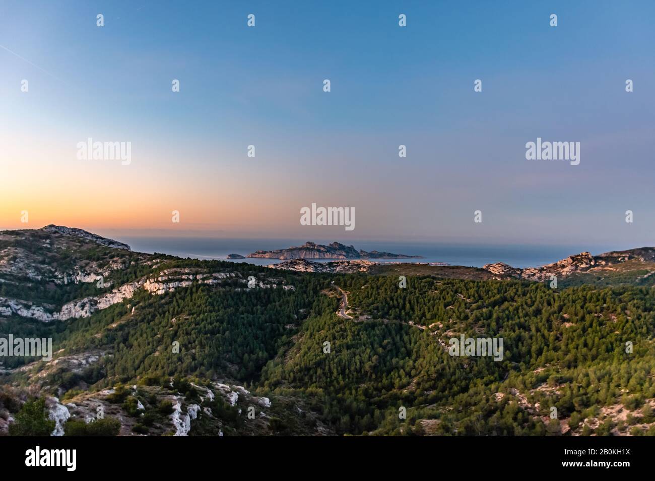 Sonnenaufgang in Calanque de Morgiou (Marseille, Frankreich): Der atemberaubende Blick auf die Bergwelt der Klippen und die Insel Riou in der Ferne unter Th Stockfoto