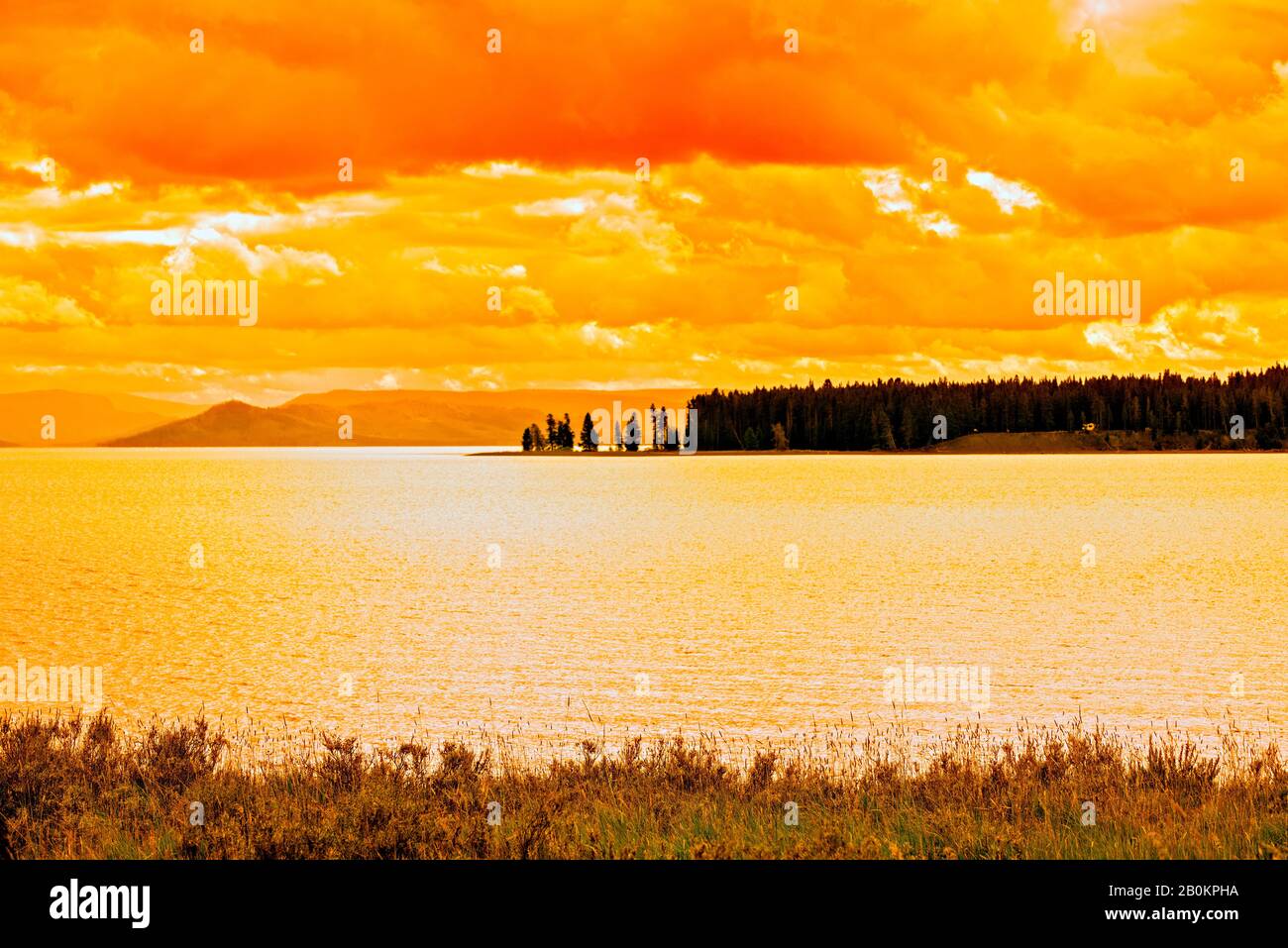 Bernsteinlicht erfüllt den bewölkten Himmel und den See. Ein warmes, friedliches Gefühl. Stockfoto