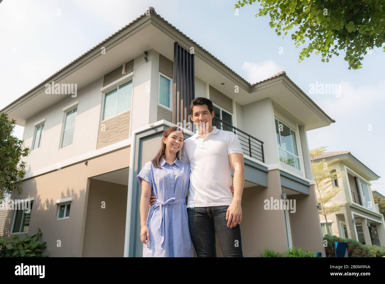 Porträt des jungen asiatischen Paares, das zusammen steht und umarmt und vor ihrem neuen Haus glücklich aussieht, um neues Leben zu beginnen. Familie, Alter, Zuhause, echte Esta Stockfoto