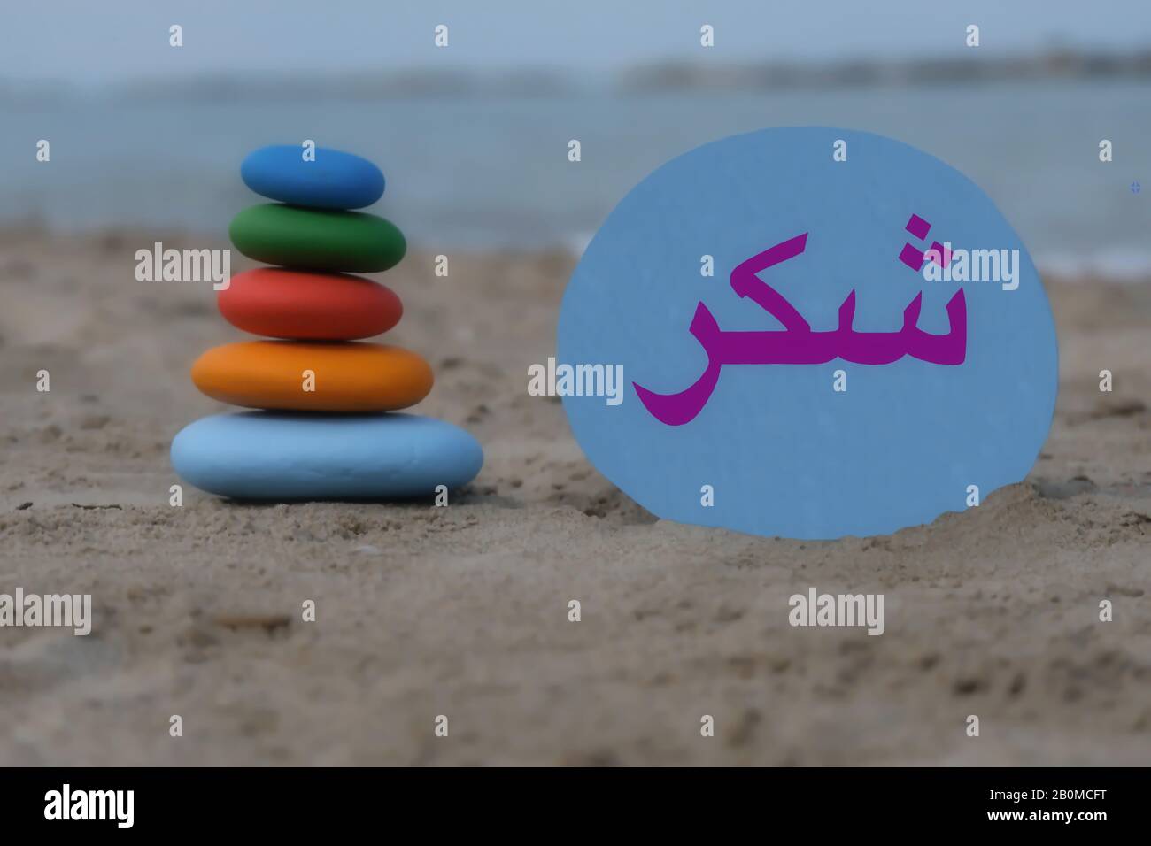 Danke in arabischer Sprache mit kreativer Steinkomposition am Strand Stockfoto