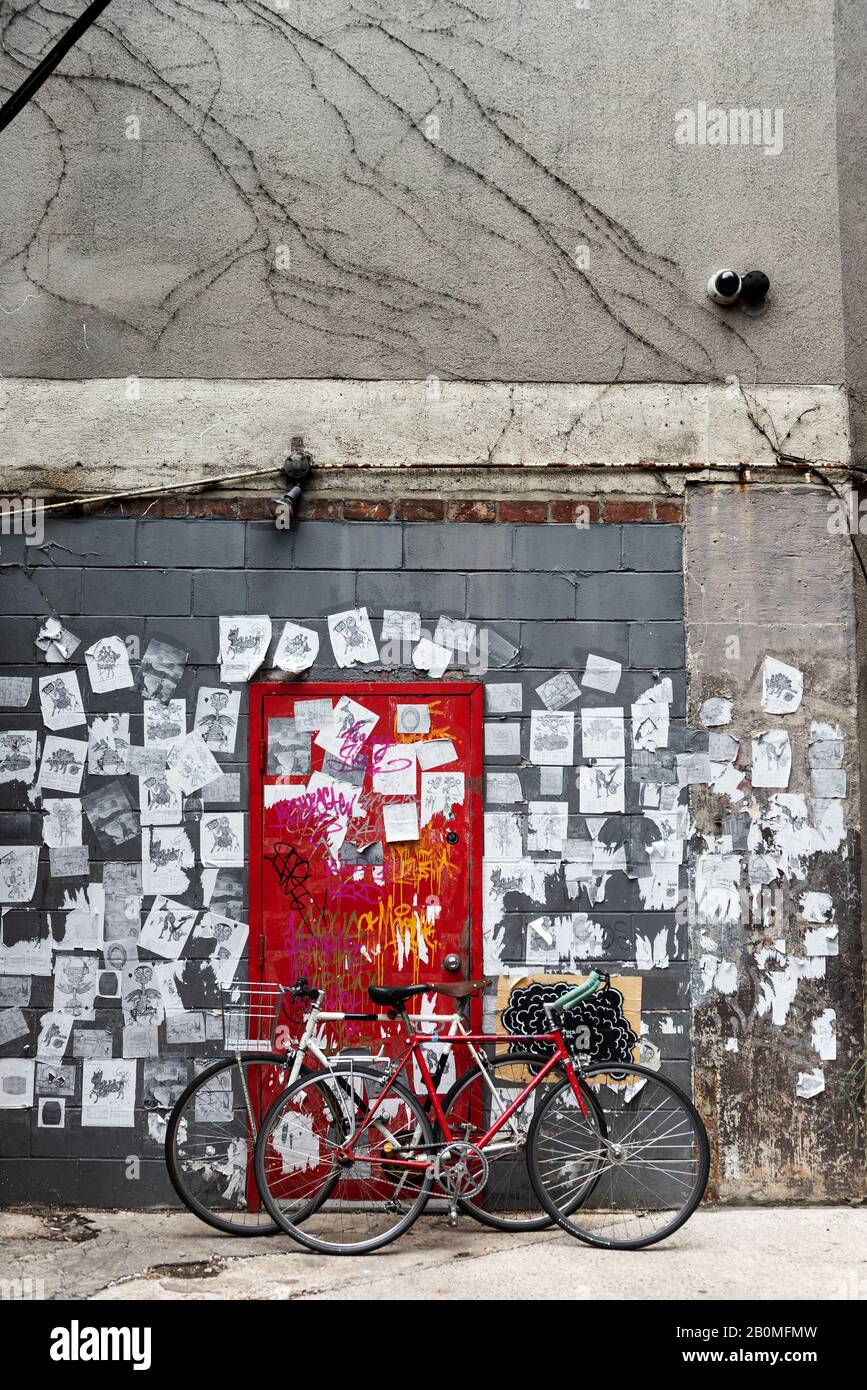 Fahrräder werden vor einer roten Tür in der Lower East Side, New York City, geparkt. Stockfoto