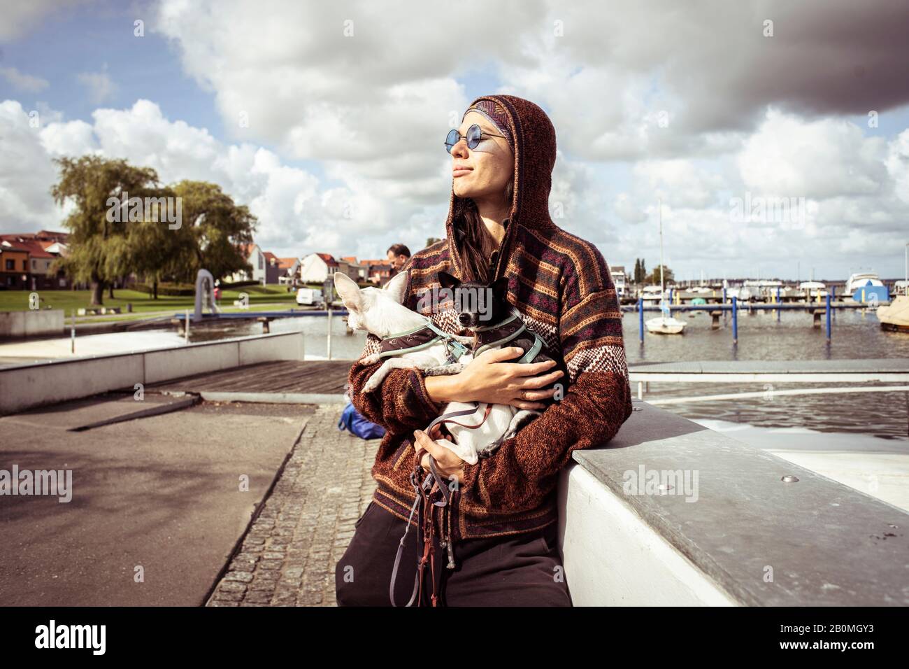 Starke Frau in Sonnenbrillen von Booten hält zwei Hunde im Sonnenlicht Stockfoto