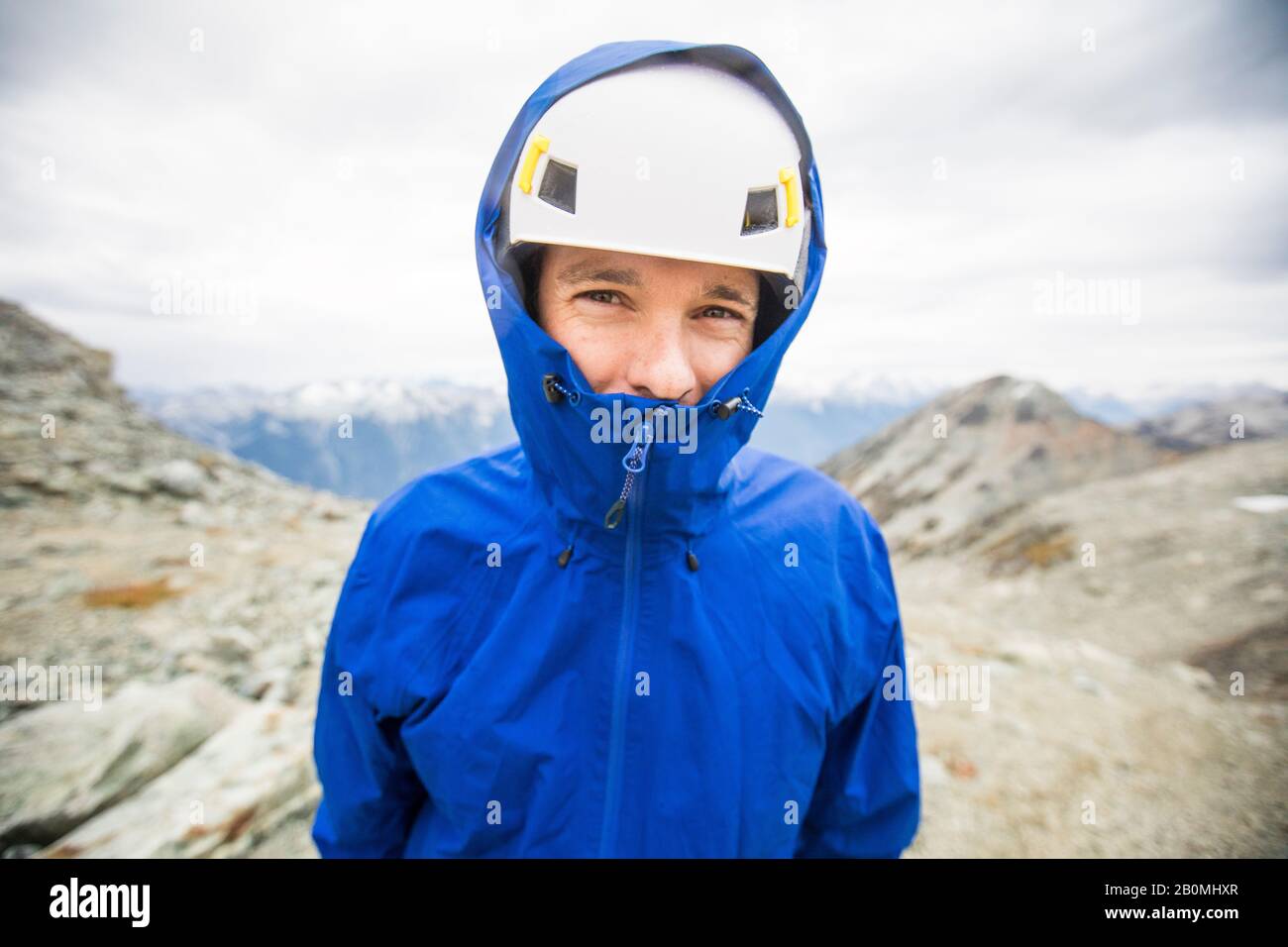 Porträt des Bergsteigers mit Helm und Regenjacke. Stockfoto