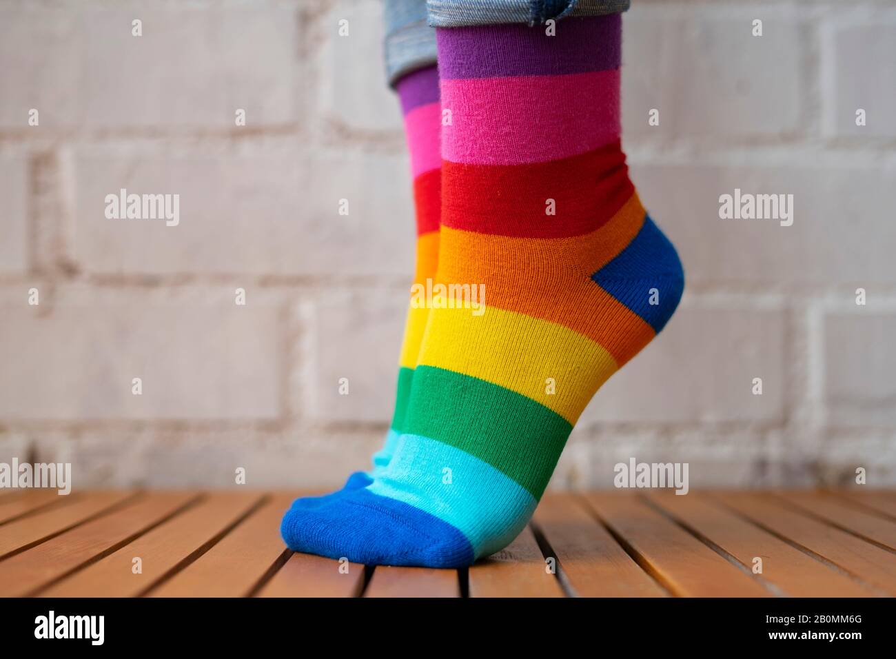 Füße stehen auf Zehenspitzen mit farbigen Socken. Das Konzept von Pride Socken. Stockfoto