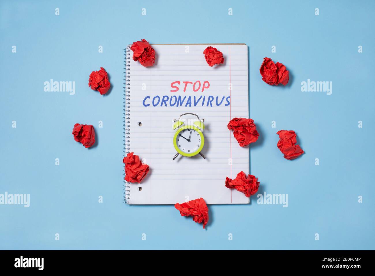 Beenden Sie den Text von Coronavirus, der auf dem geöffneten Notebook und dem Wecker geschrieben wurde Stockfoto