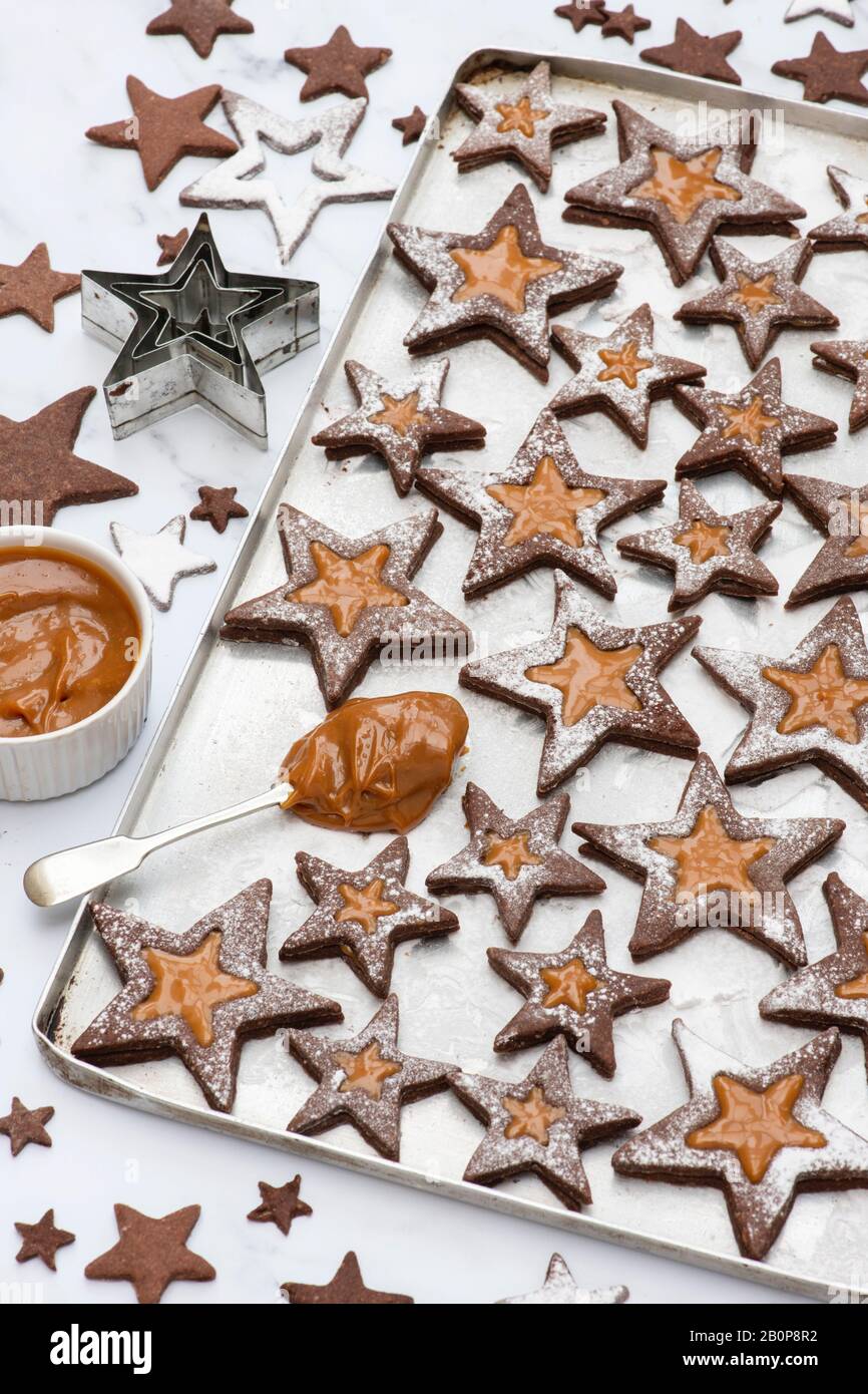 Hausgemachte Schokoladenkaramel-Star linzer Plätzchen. Schokolade und Karamell-Sandwichgebäcke mit Puderzucker auf weißem Hintergrund Stockfoto