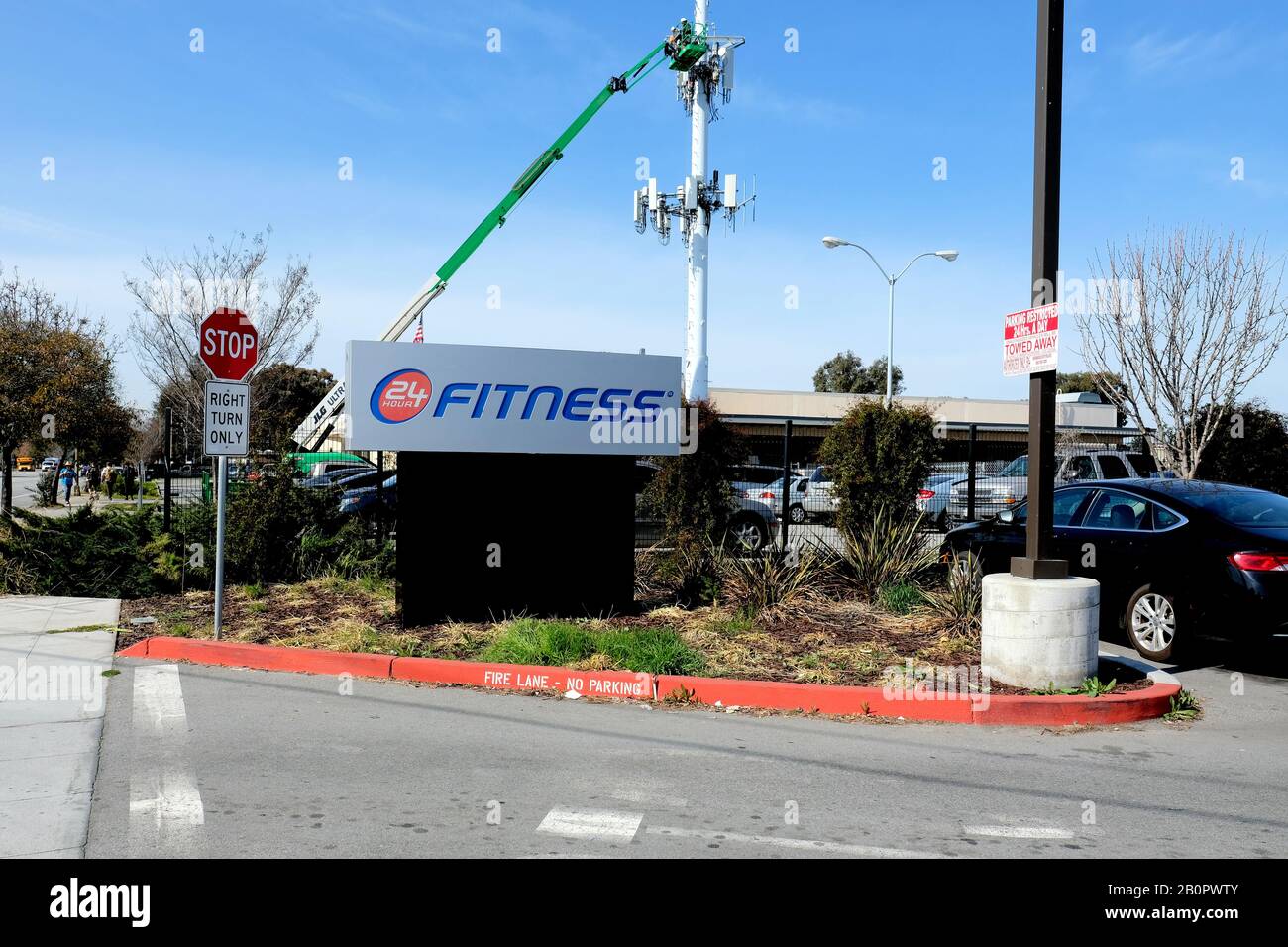 Melden Sie sich auf dem Parkplatz für 24-Stunden-Fitness in Redwood City, Kalifornien an. Teleskop-Aufzug mit einem Servicetechniker für die Arbeit an einem Handyturm. Stockfoto