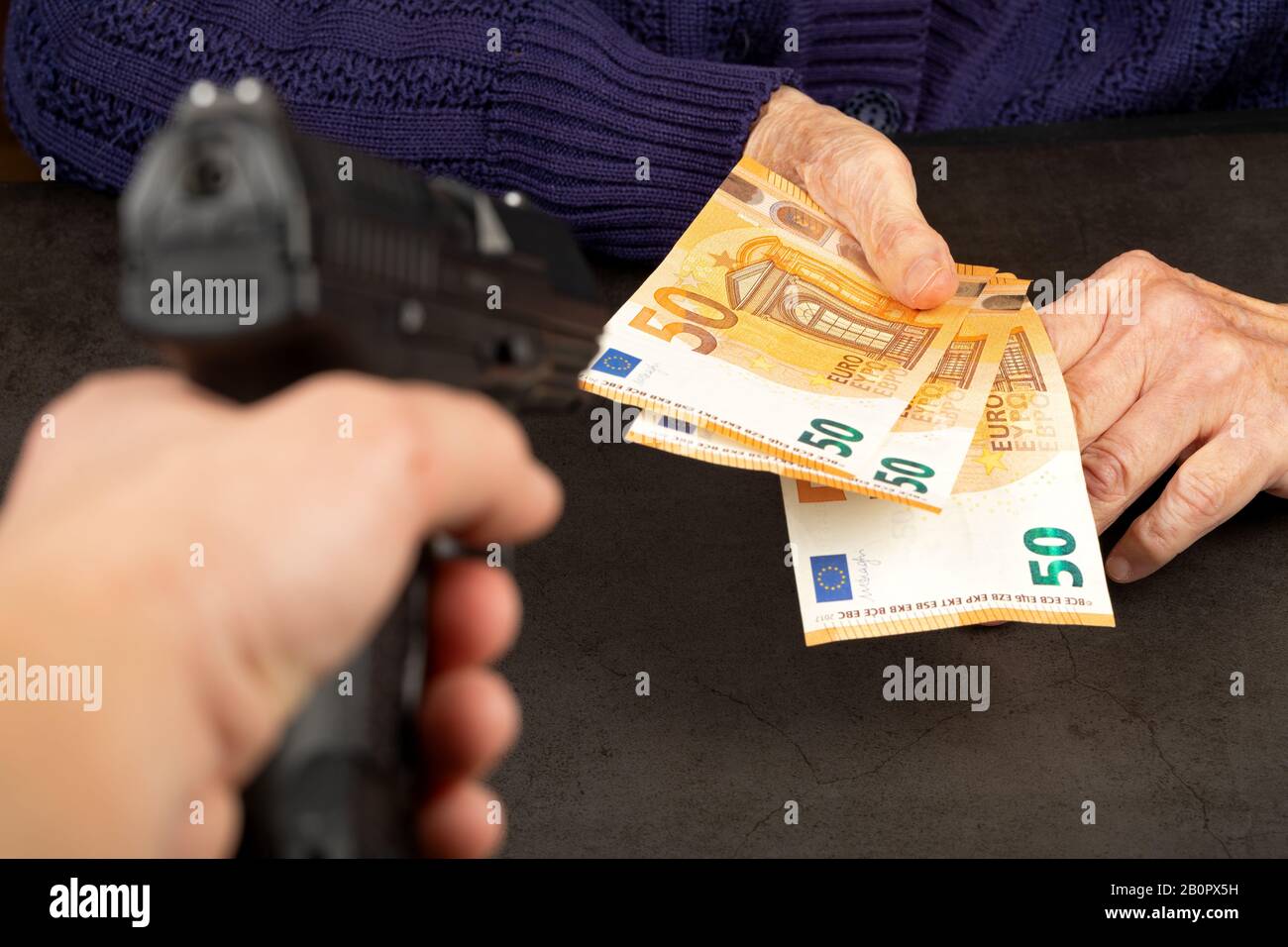 Dieb zeigt Handfeuerwaffe auf eine ältere Frau Stockfoto