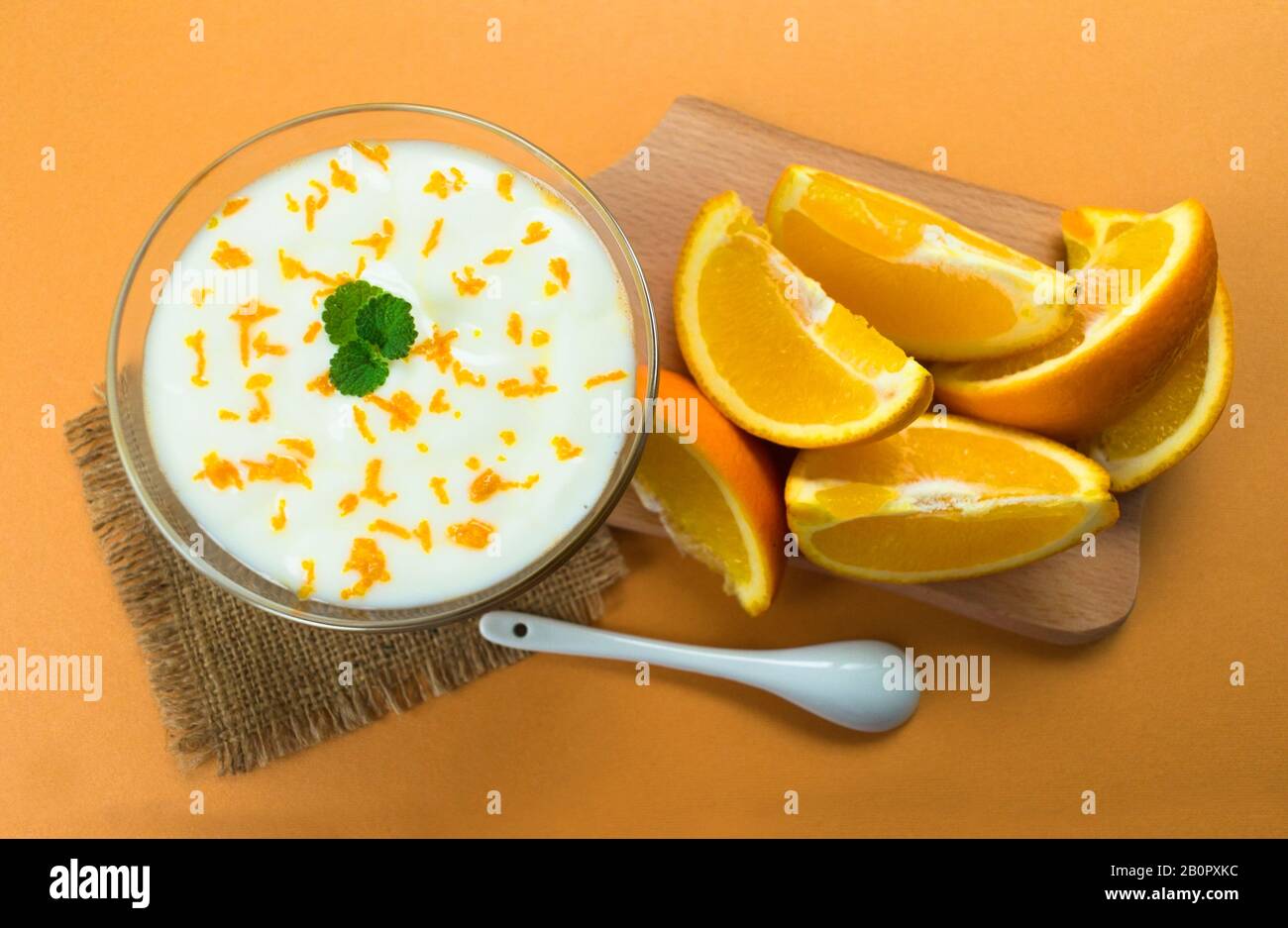 Leckerer Joghurt mit orangefarbenem Smoothie auf orangefarbenem Hintergrund. Draufsicht. Stockfoto