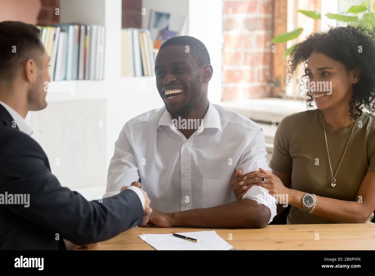 Glücklicher afroamerikanischer Paar-Manager, Realtor, Banker, Makler bei Treffen im Büro, lächelnder Mann und Frau, die Immobiliengeschäfte machen, Käufer Stockfoto