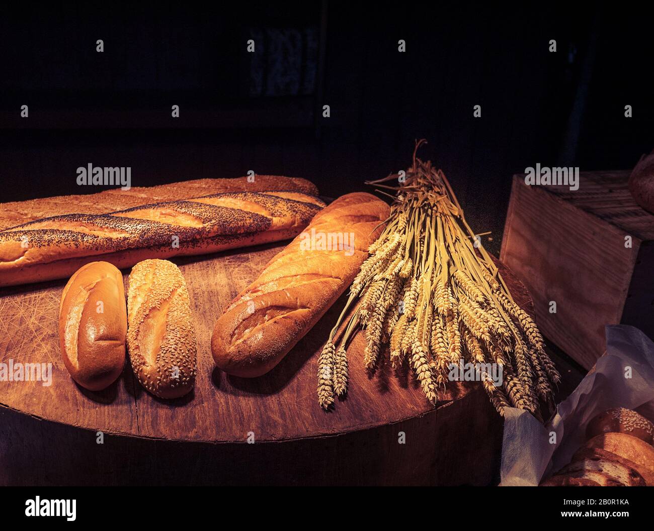 Frisch gebackenes traditionelles Brot auf Holztisch mit dunklem Hintergrund und Kopierraum Stockfoto