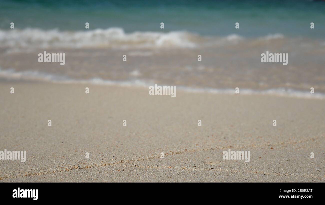 Sanfte Welle des blauen Meeres, klares Wasser am weißen Sandstrand mit Kopienfläche. Sommer Meer Sandstrand für Urlaub Hintergrundtapete Stockfoto