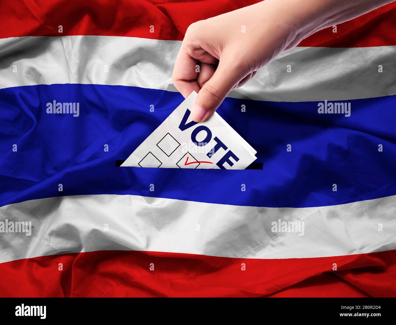 Demokratie und Wahlen in Thailand Konzept: Nahaufnahme einer Person, die bei Wahlen eine Stimme abgegeben hat, während sie auf Leinwand gewählt wurde. Hintergrund der thailändischen Flagge. Stockfoto