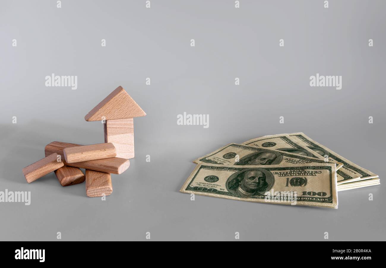 Hypothekengeschäft Konzept. Investitionen in Waren oder Immobilien. Auf grauem Hintergrund Geld und Holzwürfel. Stockfoto