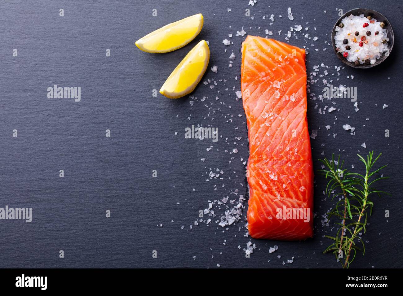 Lachsfilet mit Meersalz, Zitrone auf schieferdunklem Hintergrund. Kopierbereich. Draufsicht. Stockfoto