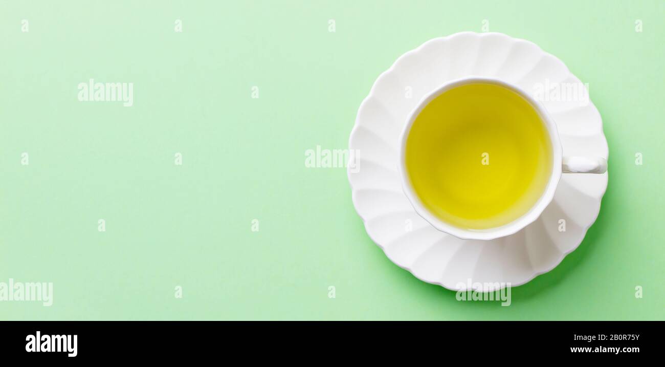 Grüner Tee in einer weißen Tasse auf pastellgrünem Hintergrund. Draufsicht. Kopierbereich. Stockfoto