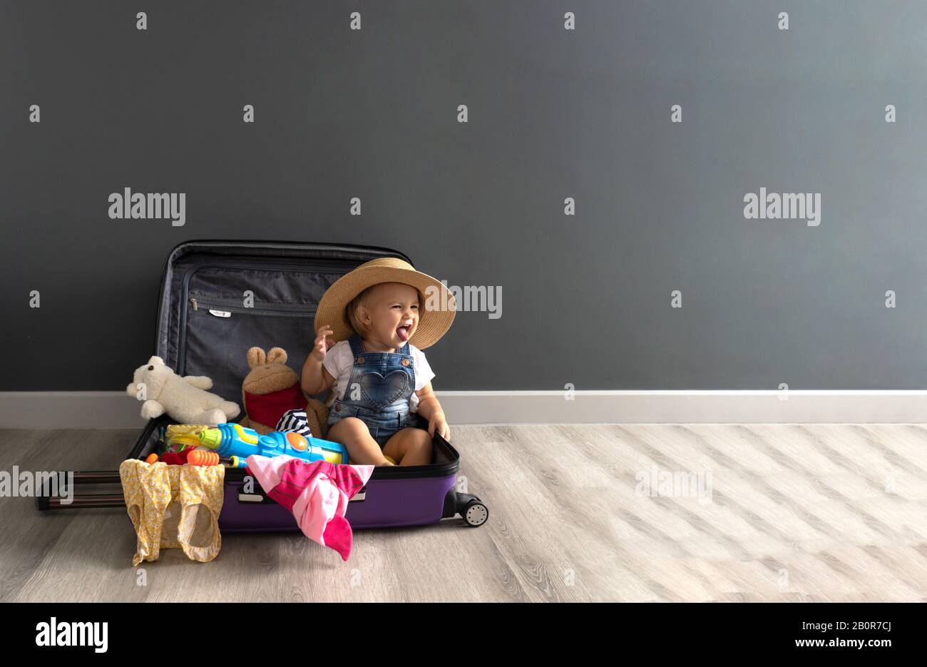 Kleines süßes Mädchen sitzt in einem Koffer, der auf den Sommer wartet Stockfoto