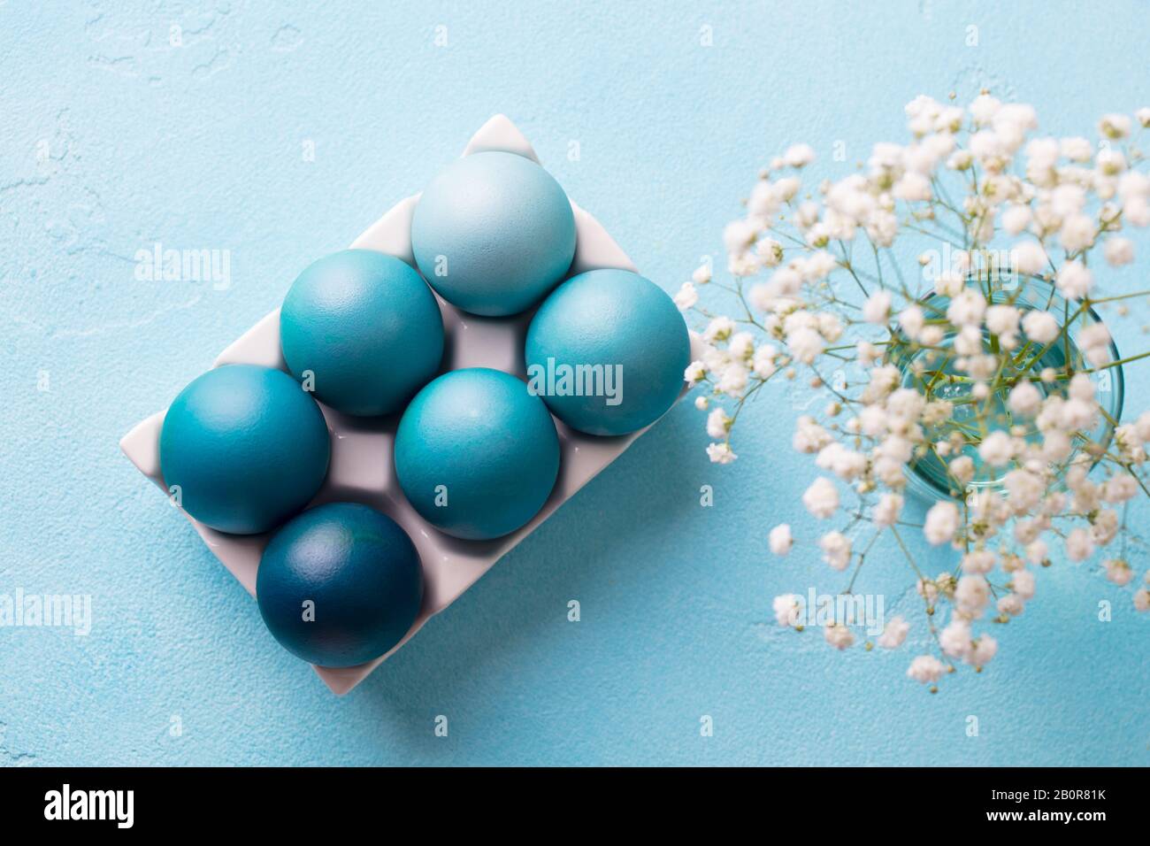 Bunte Ostereier in einem Eikasten aus Porzellan mit weißen Blumen auf blauem Grund. Draufsicht. Stockfoto