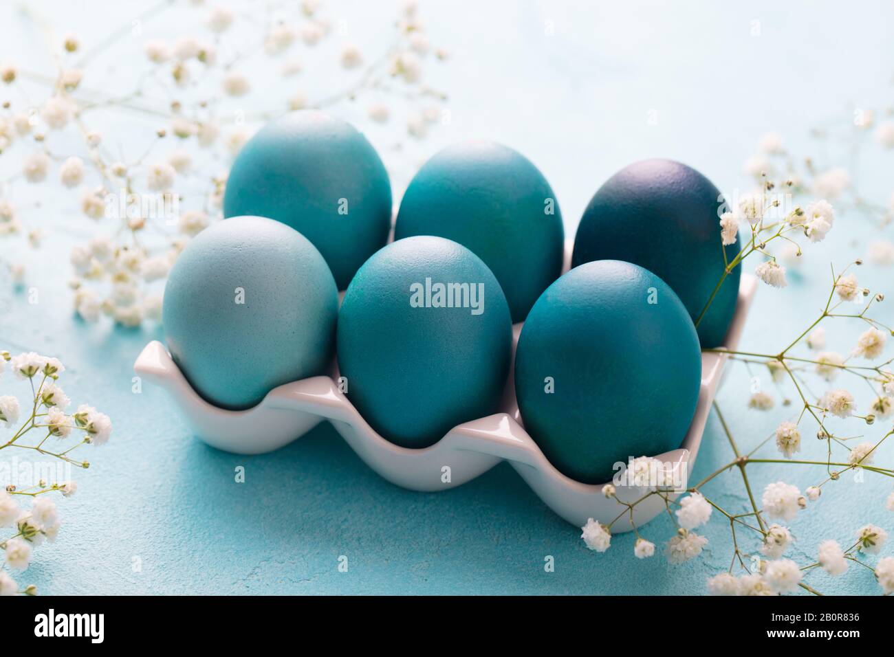 Bunte Ostereier in einem Eikasten aus Porzellan mit weißen Blumen auf blauem Grund. Nahaufnahme. Stockfoto