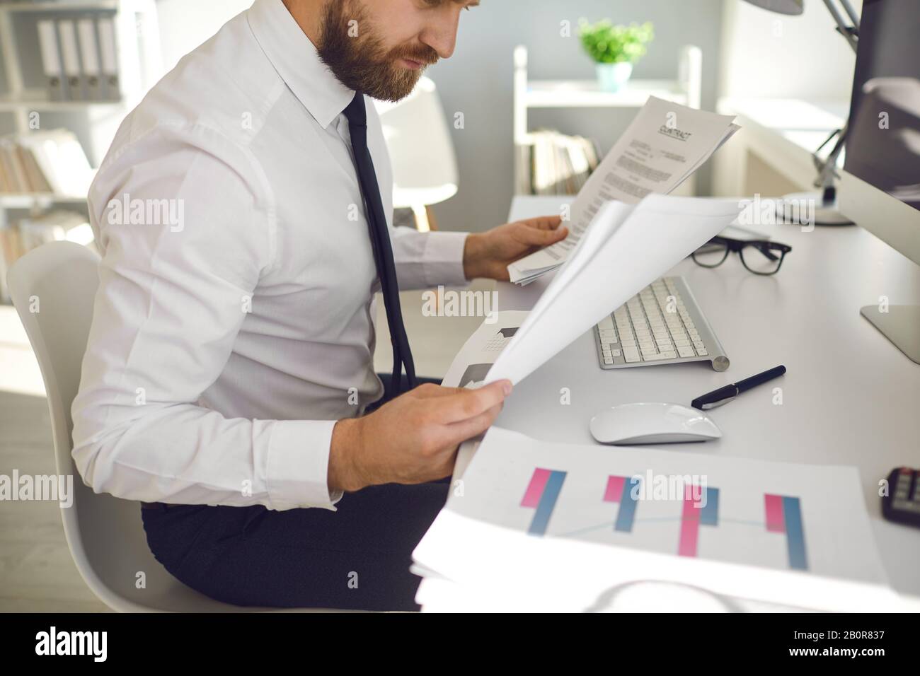 Büroarbeit ist gesichtslos. Der Geschäftsmann arbeitet an einem Tisch mit einem Computer im Büro. Stockfoto