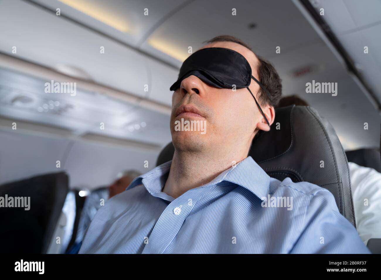 Junger Mann Schläft Mit Schlafmaske Im Flugzeug Stockfoto