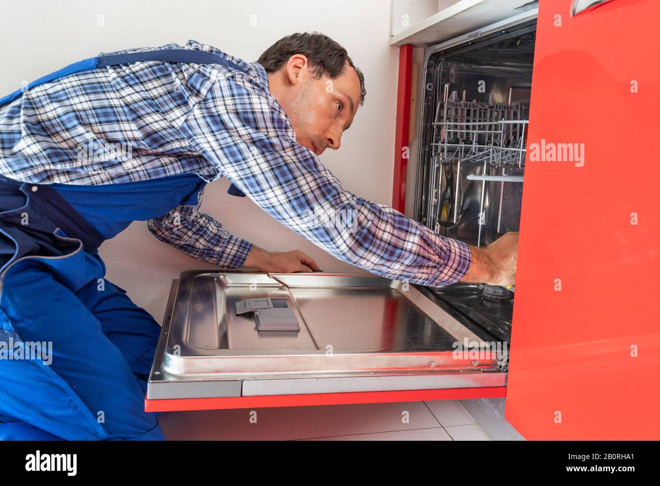 Foto Des Reparaturwerkers, Der Den Geschirrspüler In Der Küche Untersucht Stockfoto