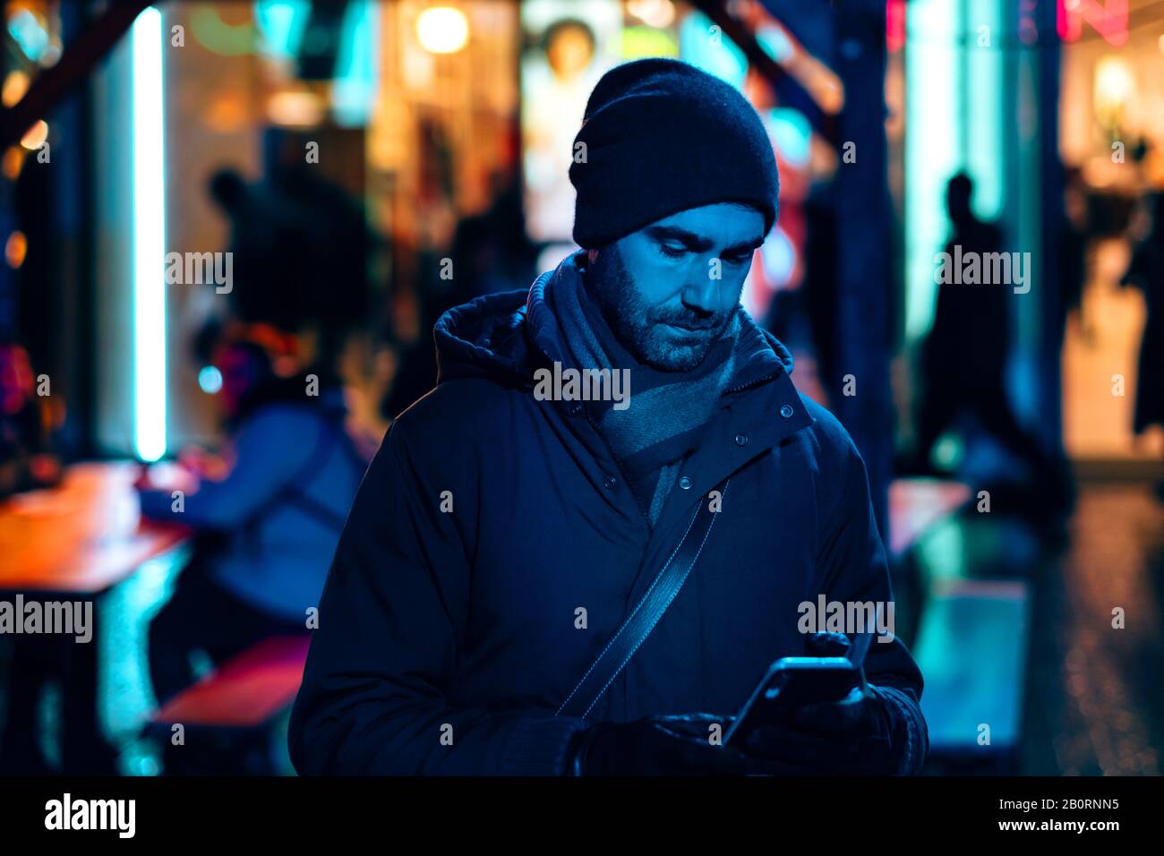 Man kann nachts in der Stadt mit einem Handy draußen sein, das von den Neonlichtern umgeben ist Stockfoto