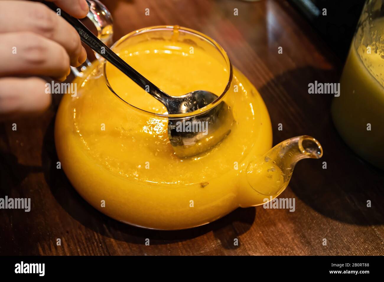 Vitamin gesunder Meeresbuckdorntee in einer kleinen Glaskanne mit frischen rohen Sanddornbeeren und Zimtstäbchen, Kochvorgang. Stockfoto