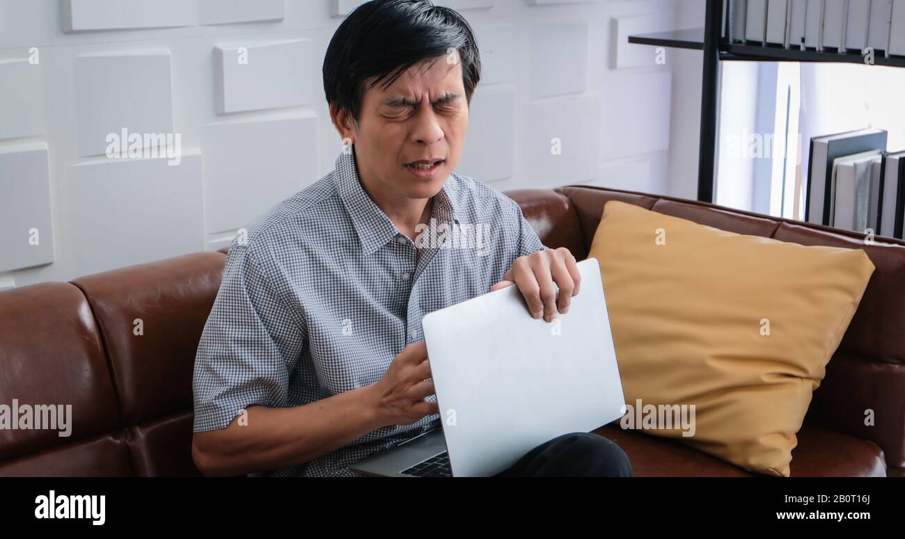 Die alten Asiaten arbeiten hart, bis sie gestresst werden und er sich schlecht auf seinem Herzen fühlt und er jemanden zur Hilfe ruft Stockfoto