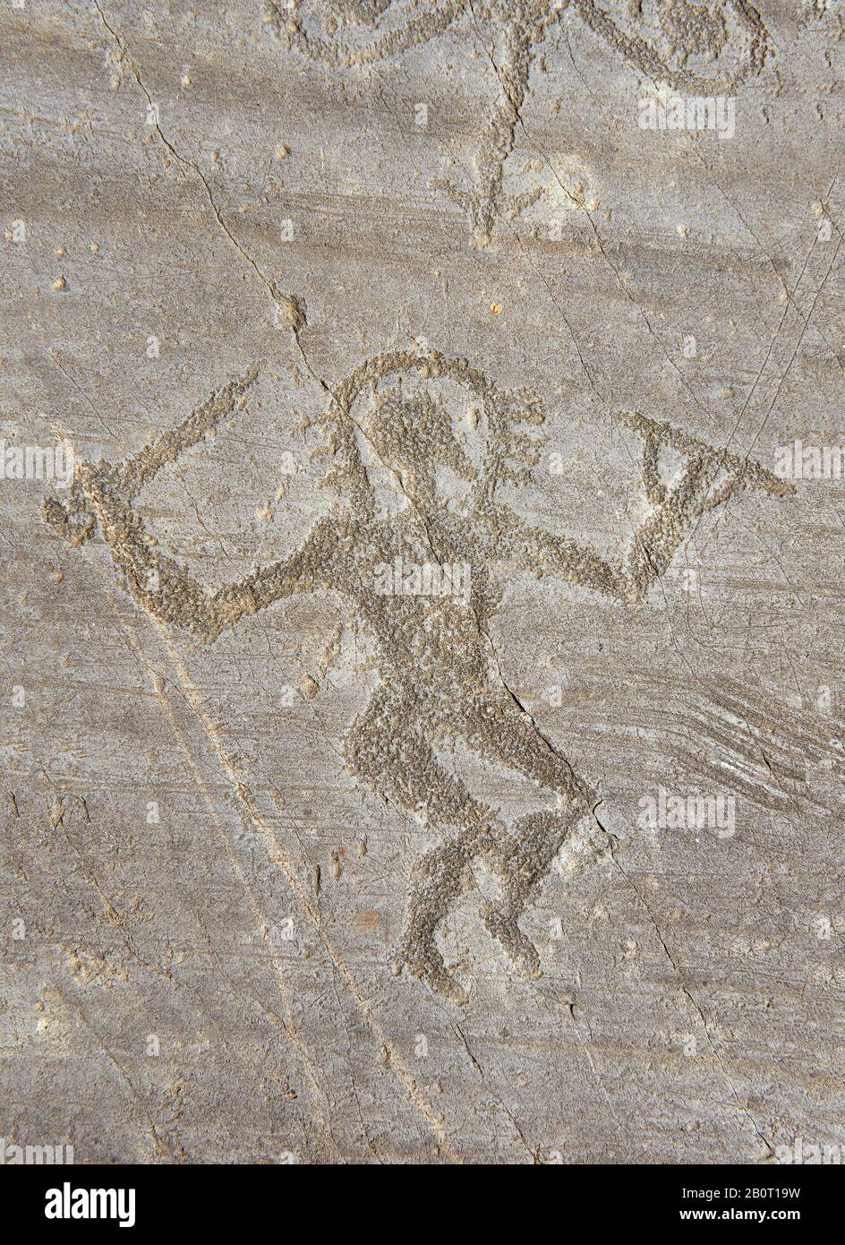 Petroglyph, Felsschnitzerei, eines Kriegers, der mit Schwert und runder Schutzplatte tanzt und einen Halo-Helm trägt. Von den alten Camuni-Leuten geschnitzt Stockfoto