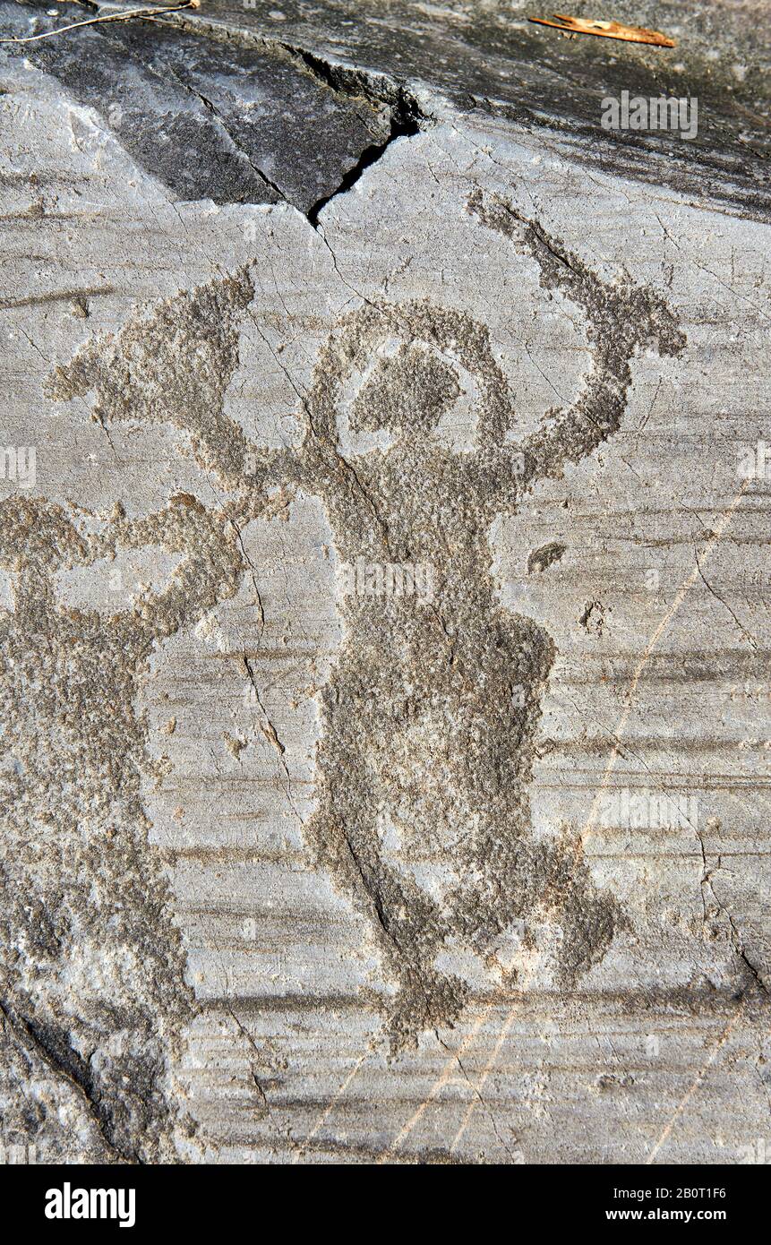 Petroglyph, Felsschnitzerei, eines Kriegers, der einen Helm trägt und Schwert und Schild trägt. Von den alten Camuni-Leuten in der Eisenzeit zwischen gehauen Stockfoto