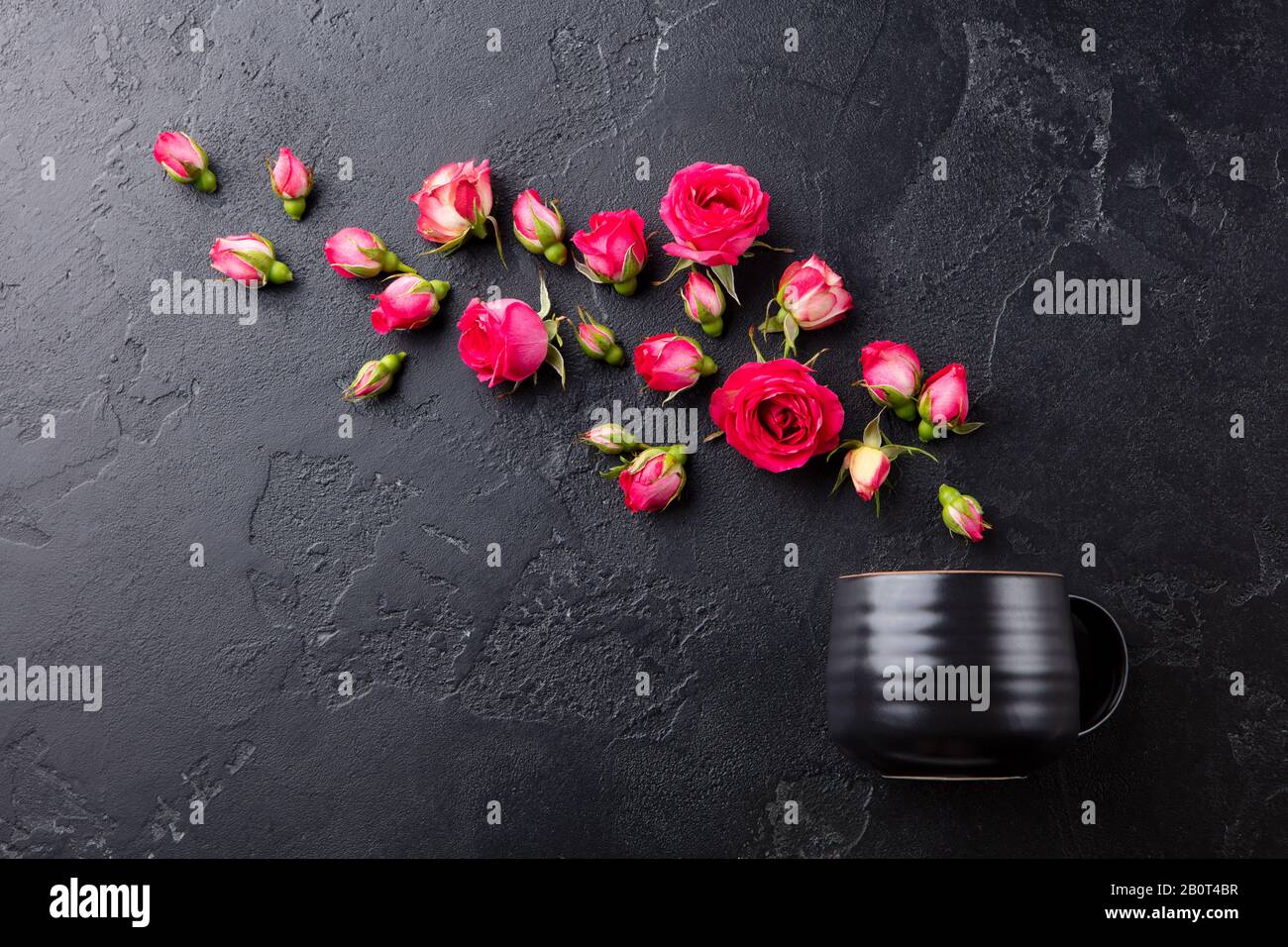 Teetasse mit frischen Rosen Blumen auf schwarzem Steingrund. Draufsicht. Kopierbereich. Stockfoto