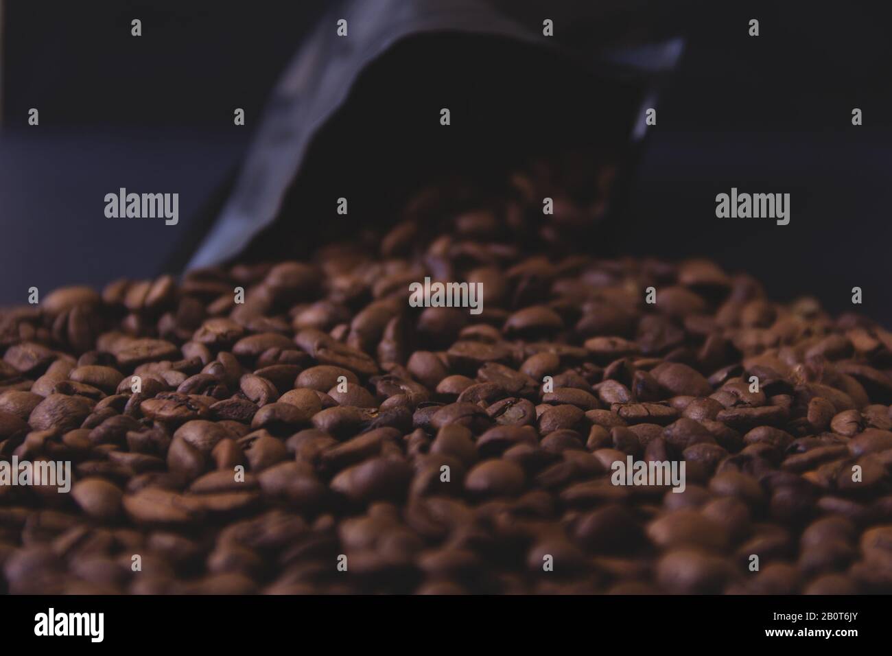 Kaffeebohnen verschütten sich aus einer schwarzen Packung. Stockfoto