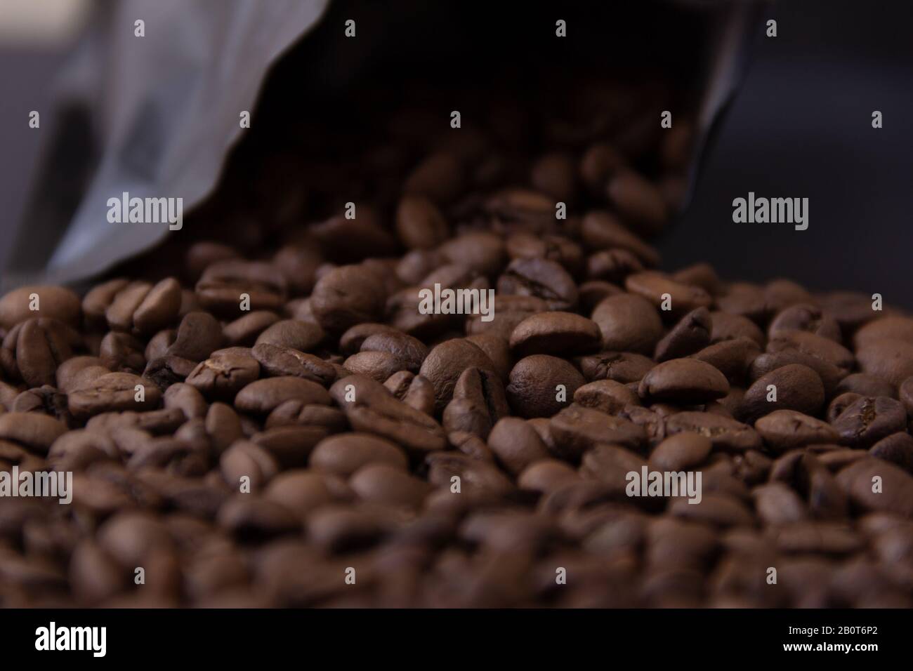 Kaffeebohnen verschütten sich aus einer schwarzen Packung. Stockfoto