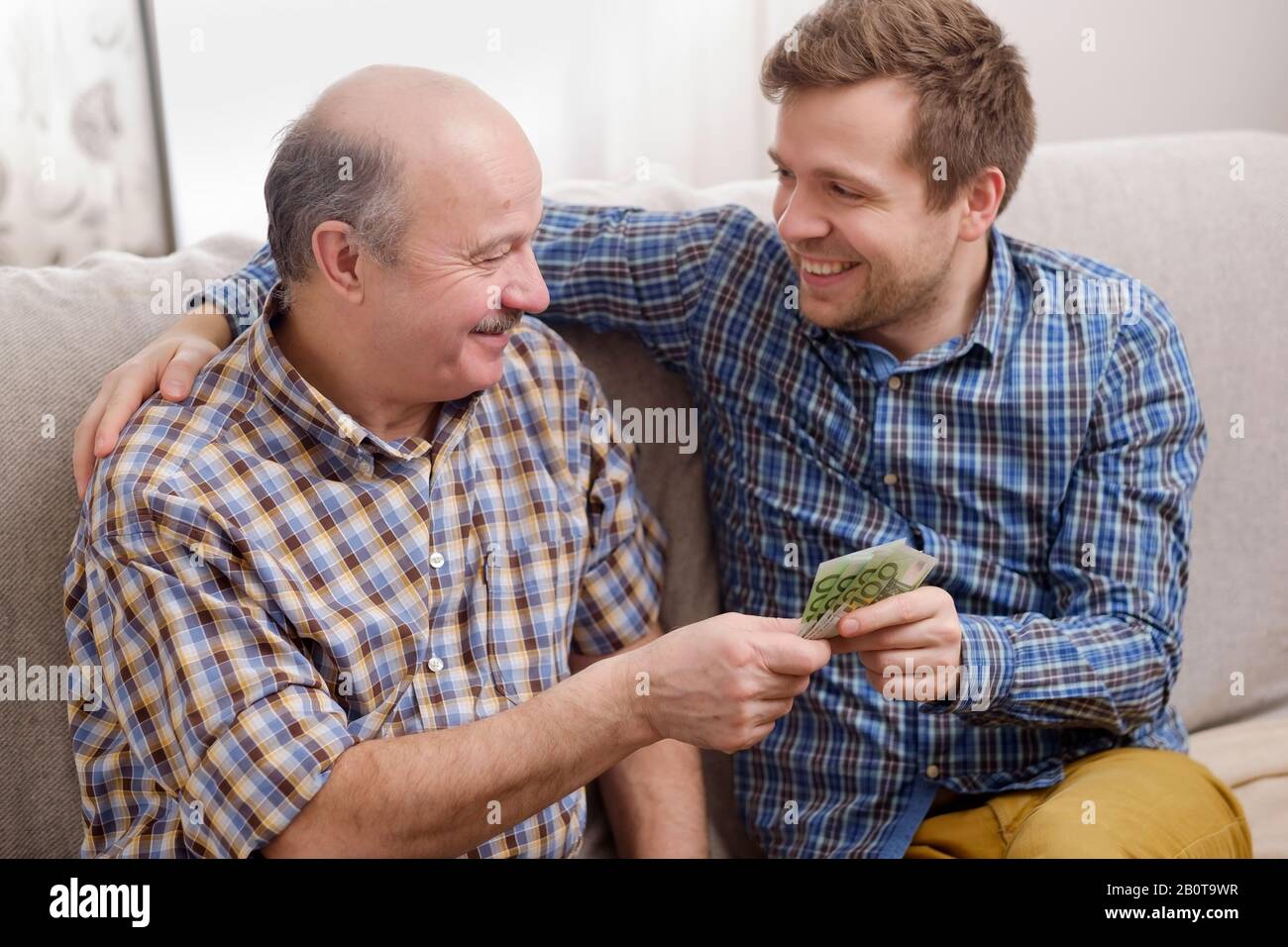 Ältere Vater verleiht Geld zu seinen erwachsenen Sohn. Er hilft seinem Kind befassen sich mit finanziellen Problemen. Stockfoto