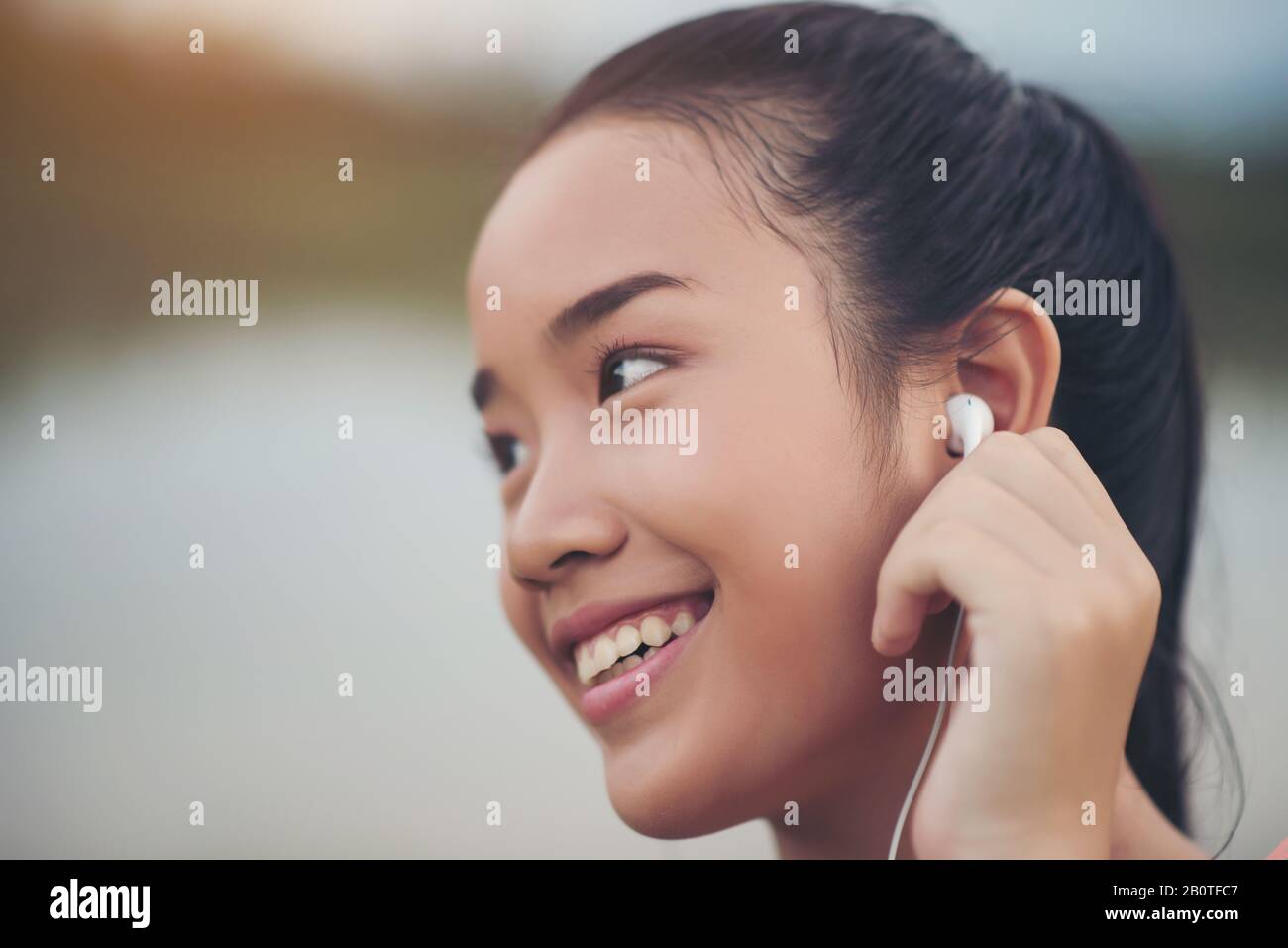 Fitnessfrau in Ohrhörern, die während ihres Trainings Musik hört und im Park Sport macht Stockfoto