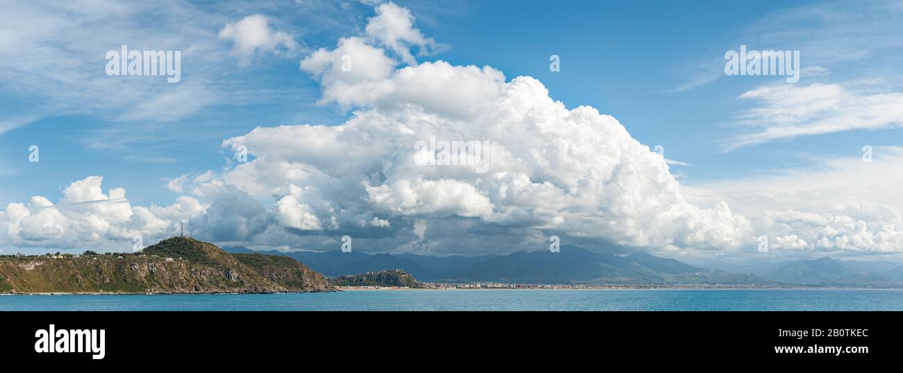 Panoramablick auf die Küste von Milazzo mit großen weißen Wolken darüber. Leicht rauschende Fotografie. Milazzo, Sizilien, Italien Stockfoto