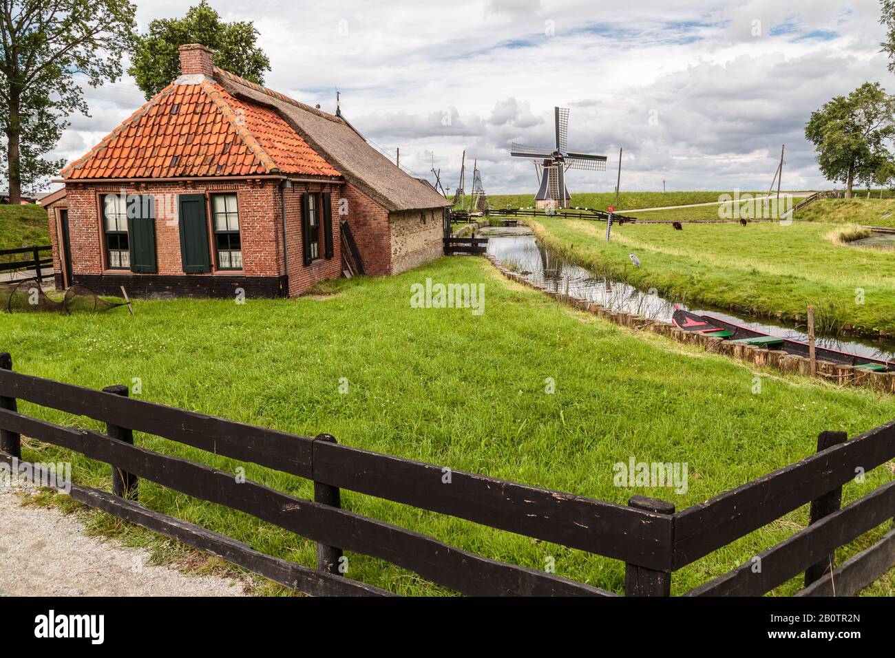 Zuiderzee Museum Enkhuizen. Malerisches holländisches Ferienhaus und Windmühle mit einem Boot am Bach. Stockfoto