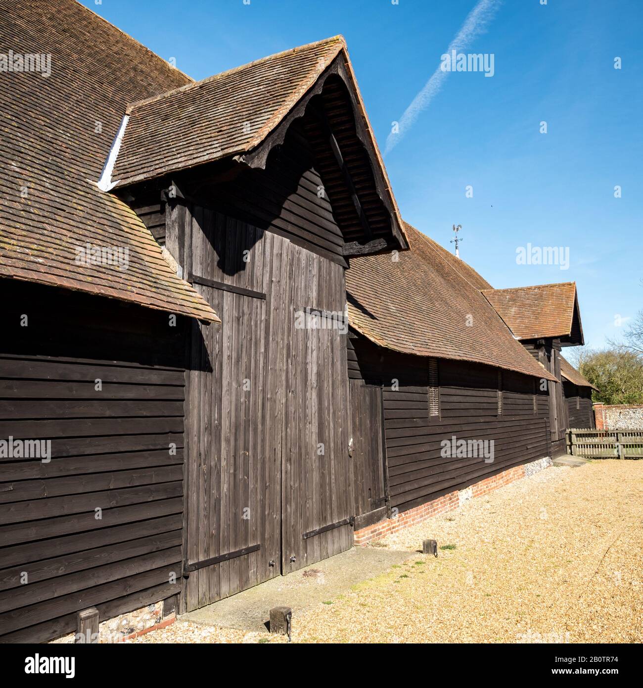 Old English Farm Barn. Das Äußere einer alten Holzscheune auf einem englischen Bauernhof in der hellen Frühlingssonne. Stockfoto