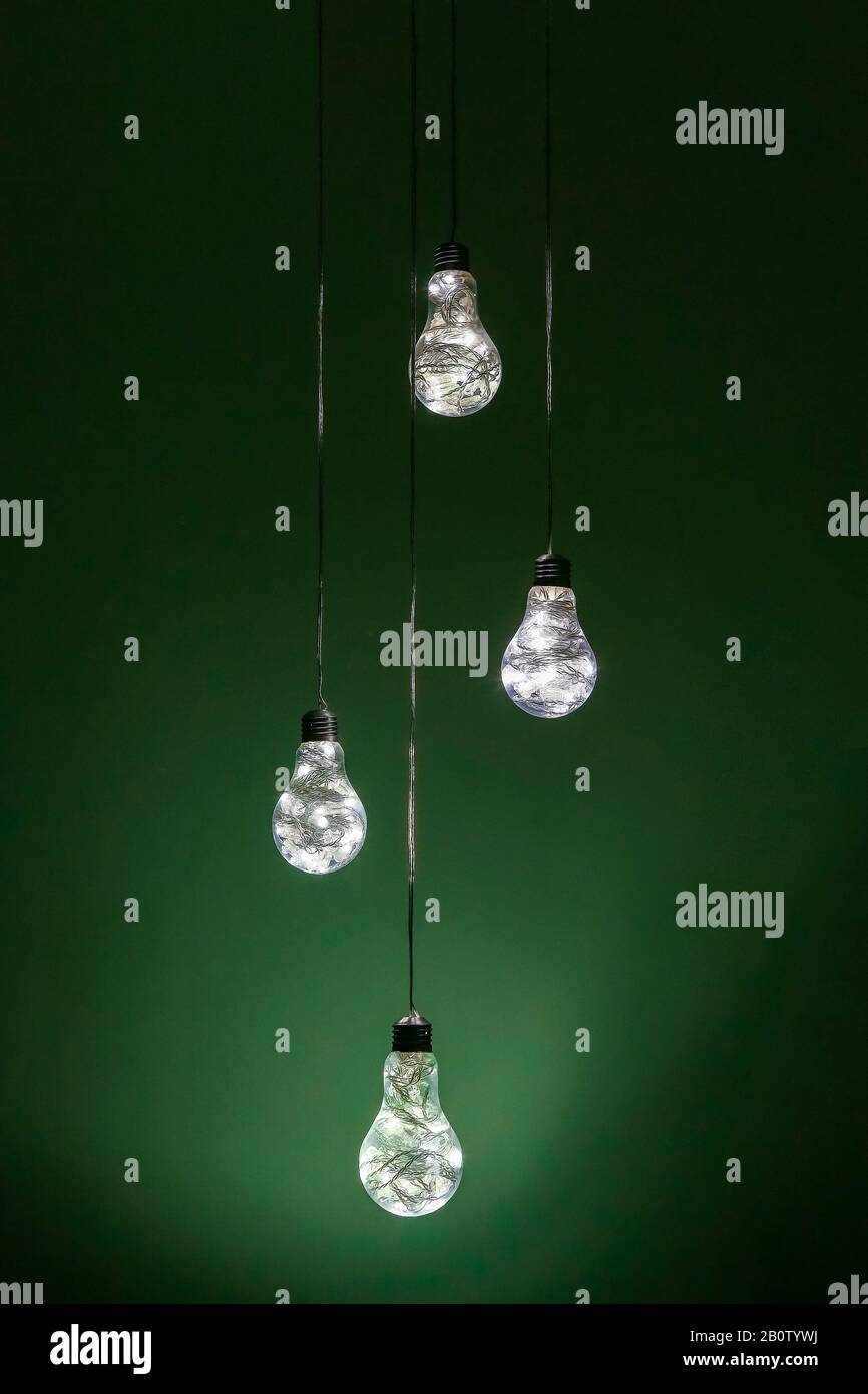 Ein Vierer von außergewöhnlichen, handgefertigten elektrischen Lampen hing vor grünem Hintergrund Stockfoto