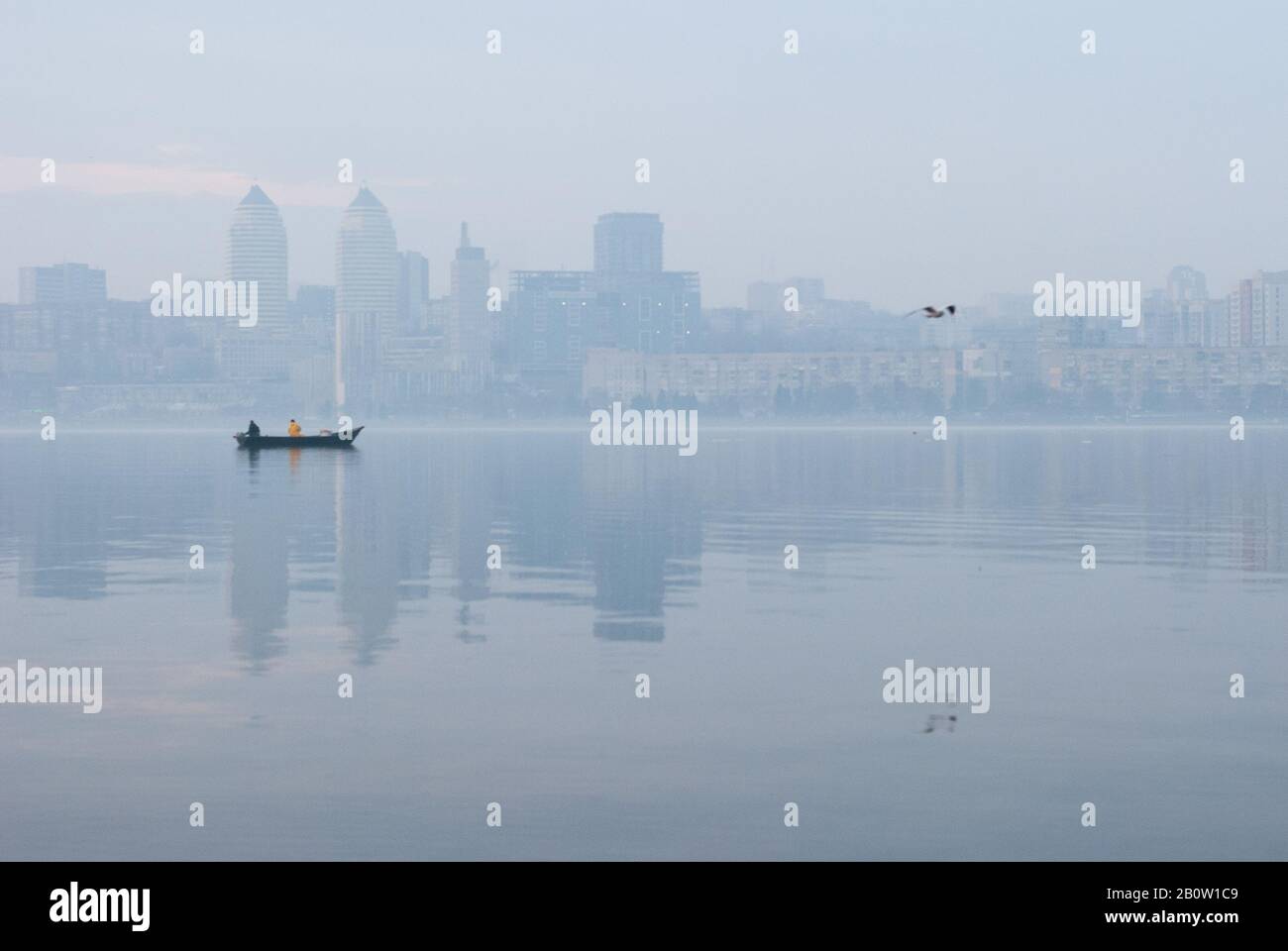 Fischerboot auf dem Dnjepr Fluss in der Ukraine vor dem Hintergrund der Stadt Dnipro im Morgennebel. Dnipro ist mit abou die viertgrößte Stadt der Ukraine Stockfoto