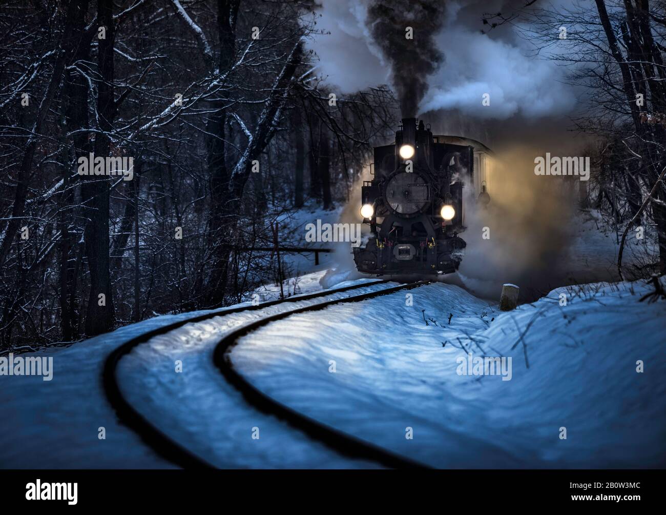 Budapest, Ungarn - Schöne Winterwaldszene mit Schnee und alter Dampflok auf der Strecke im ungarischen Wald von Huvosvolgy in der Nacht Stockfoto