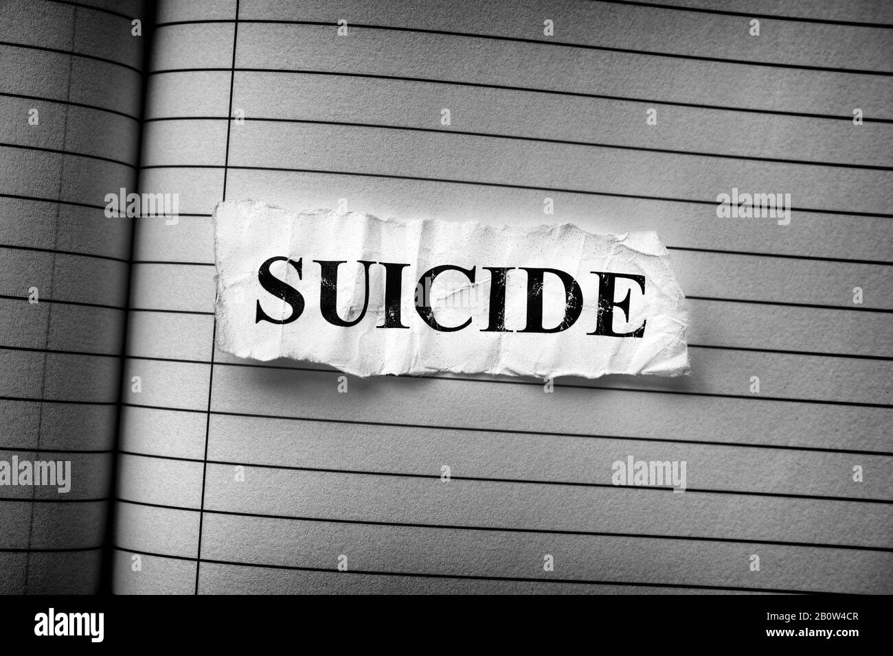 Zerknittertes Stück Papier mit dem Wort Selbstmord. Schwarzweiß. Nahaufnahme. Stockfoto
