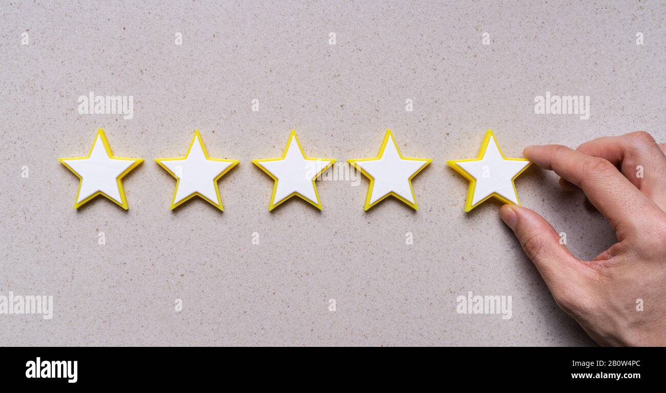 Die Hand der Person, Die Das Symbol Für Die Bewertung Von Fünf Sternen Am Schreibtisch bildet Stockfoto